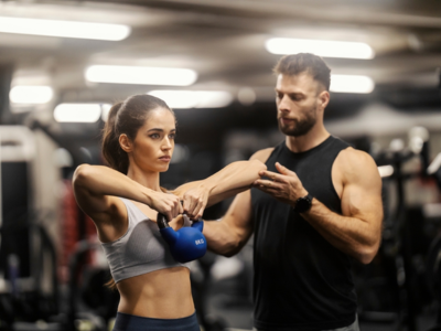 Muscle Building Trainer in Birmingham guiding client on lat pulldown machine for upper body strength training.